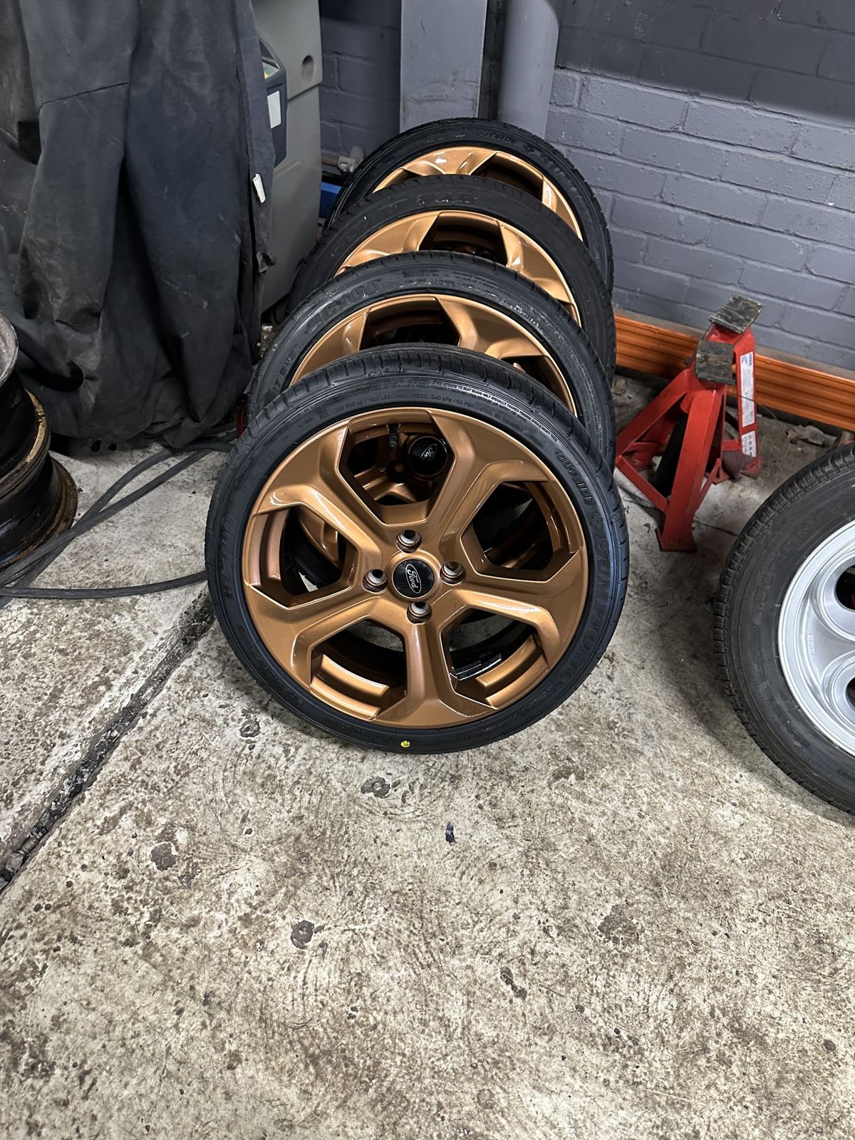 Four copper-bronze wheels with tyres stacked ready to go back on