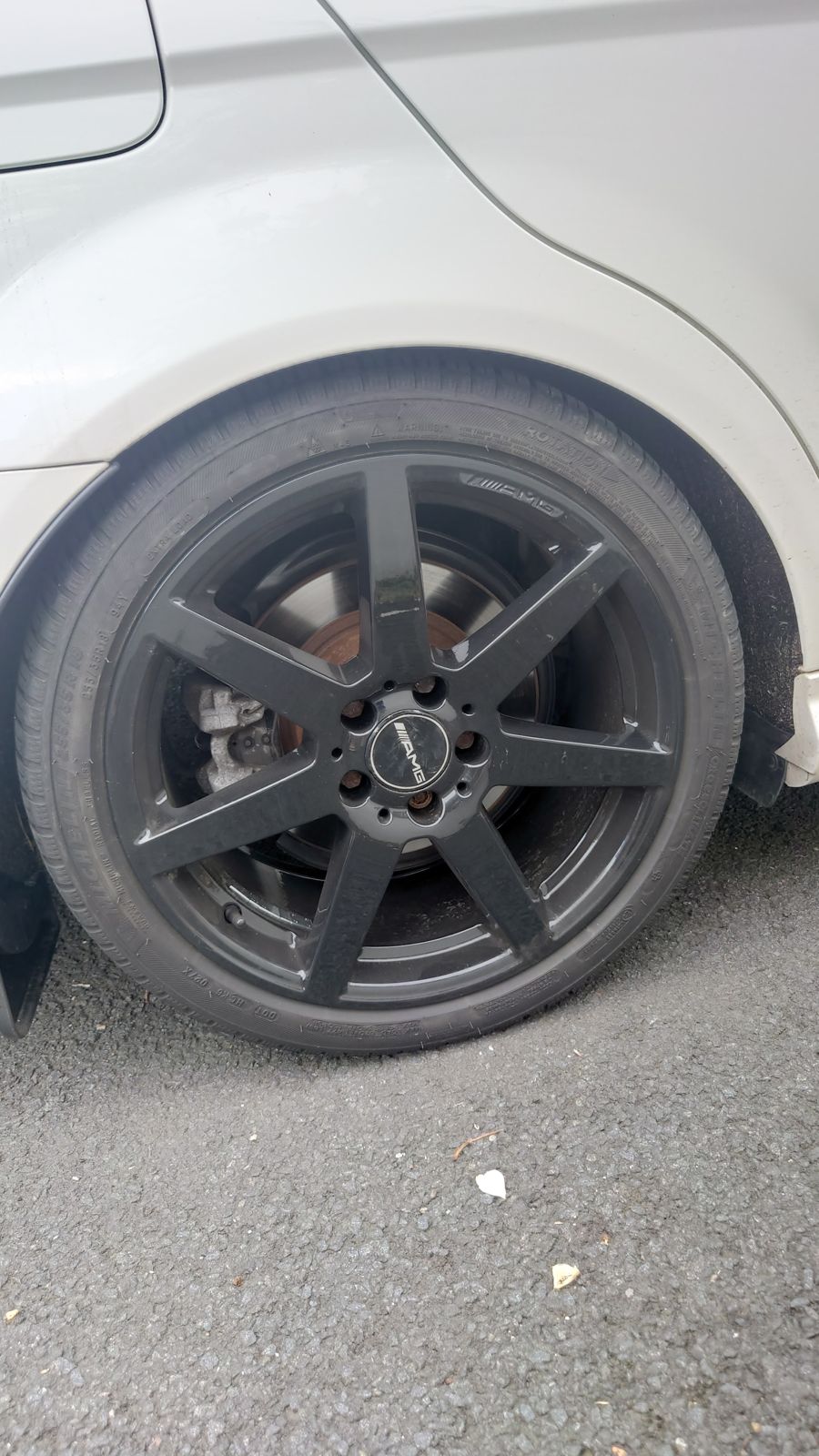 A satin-black five-spoke alloy on a white car
