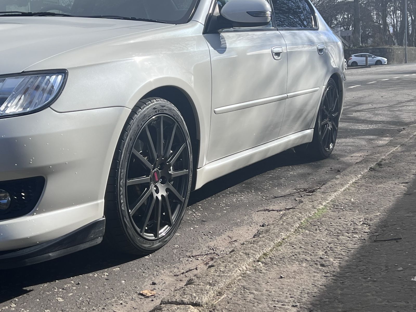 A white Subaru estate on black multi-spoke wheels